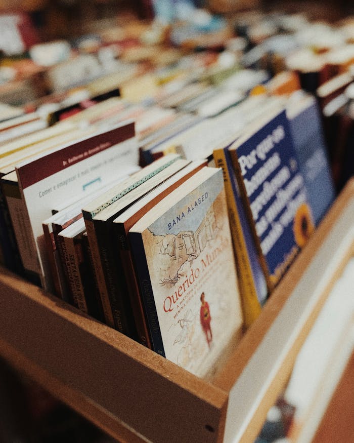 A close-up of various books neatly arranged on a wooden shelf inside a bookstore.