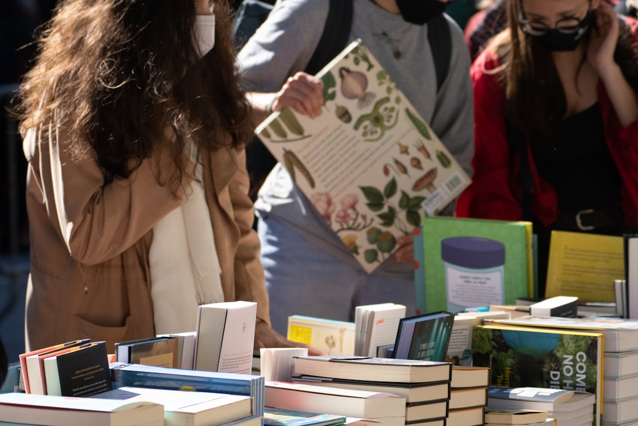 People browsing books at an outdoor book festival on a sunny day.
